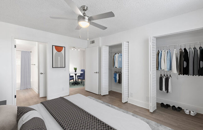 A bedroom with a bed, a chair, a wardrobe, and a ceiling fan.