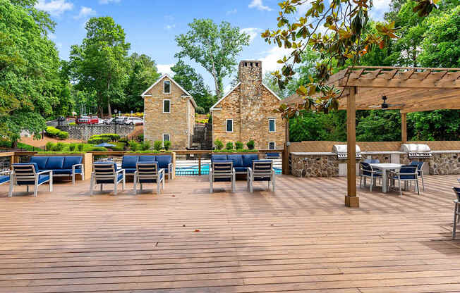 A wooden deck with chairs and tables is surrounded by trees. at Mill House at East Cobb, Georgia