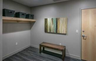 A room with a wooden bench, a painting on the wall, and a door.