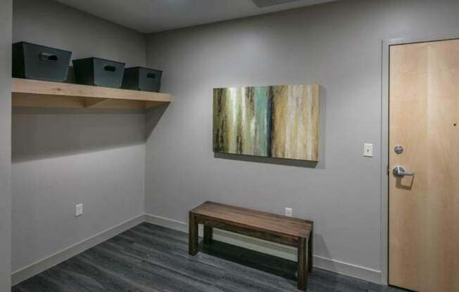 A room with a wooden bench, a painting on the wall, and a door.