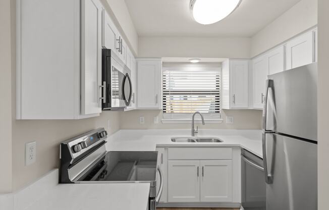 a renovated kitchen with white cabinets and stainless steel appliances