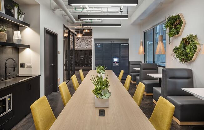 a large wooden table with yellow chairs and a kitchenette in the background