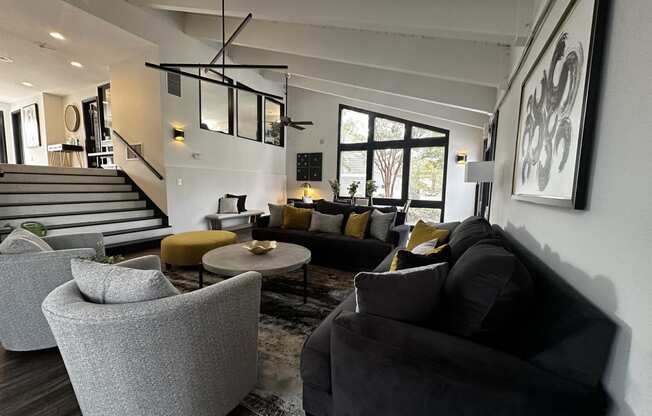 a living room with couches and chairs and a staircase