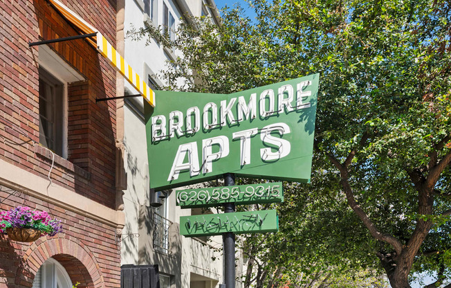 A green sign that says Brookmore Apts on it.