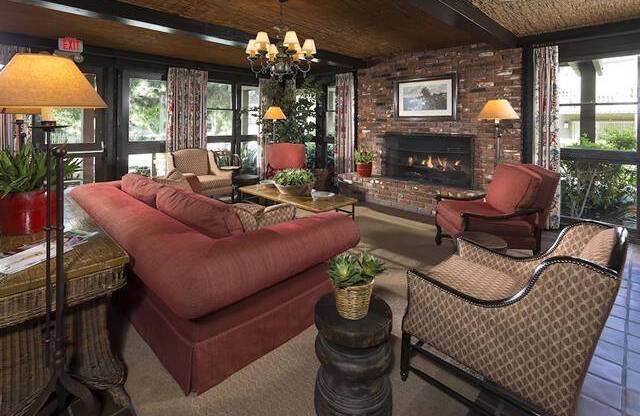 a clubhouse living room with a couch and chairs and a fireplace