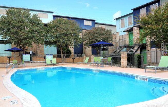 a swimming pool with chairs and umbrellas next to a building