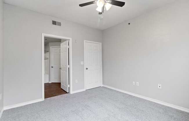 an empty bedroom with a ceiling fan and a door to a closet