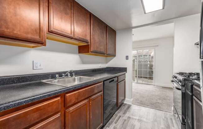 A kitchen with dark wood cabinets and a black granite countertop.