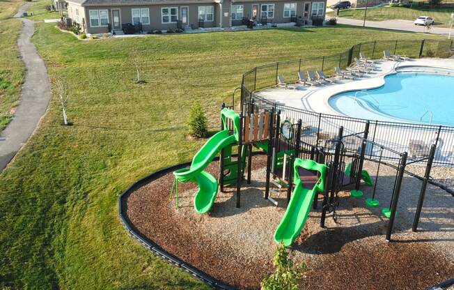 a playground with slides and a pool in front of a house