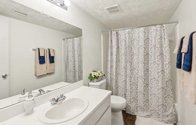 A white bathroom with a sink, toilet, and shower curtain.