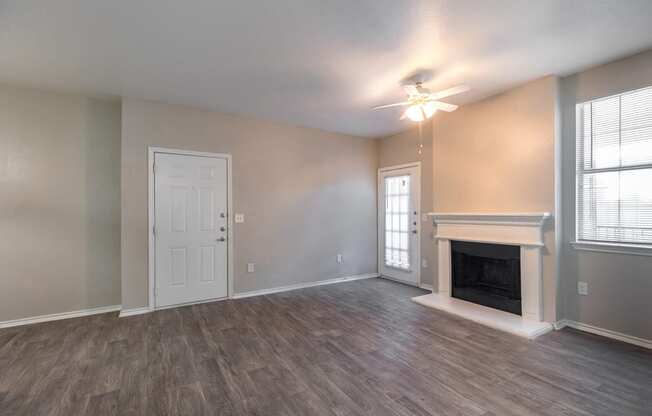 an empty living room with a fireplace and a ceiling fan