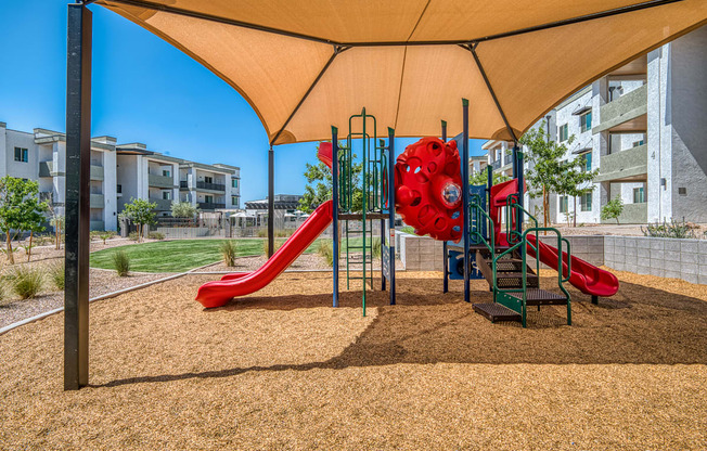 A playground with a red slide and a yellow canopy.
