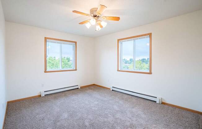 A room with a ceiling fan and two windows. Fargo, ND Summit Point Apartments