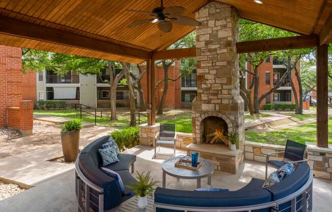 a covered patio with a fireplace and seating