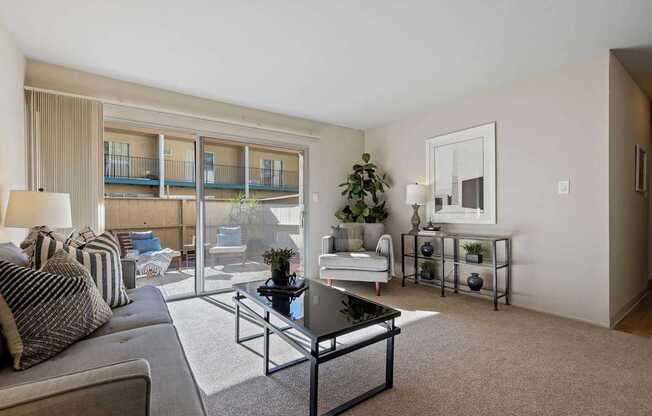 A living room with a couch, a coffee table, and a balcony.