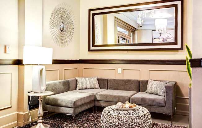 Apartment lobby with a grey couch and a round table.