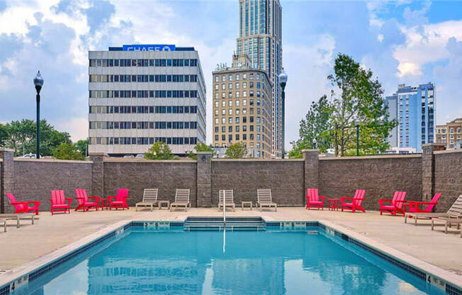 a pool with red chairs and a city in the background at Shearwood Station, New Rochelle, NY
