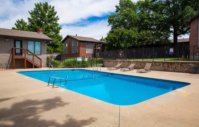 A blue swimming pool surrounded by a fence and trees.