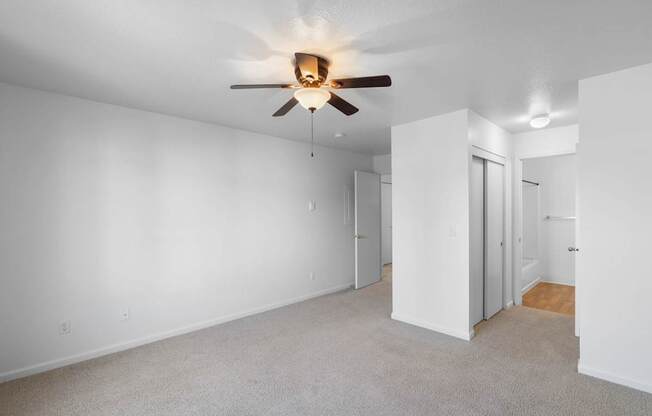 a living room with white walls and a ceiling fan