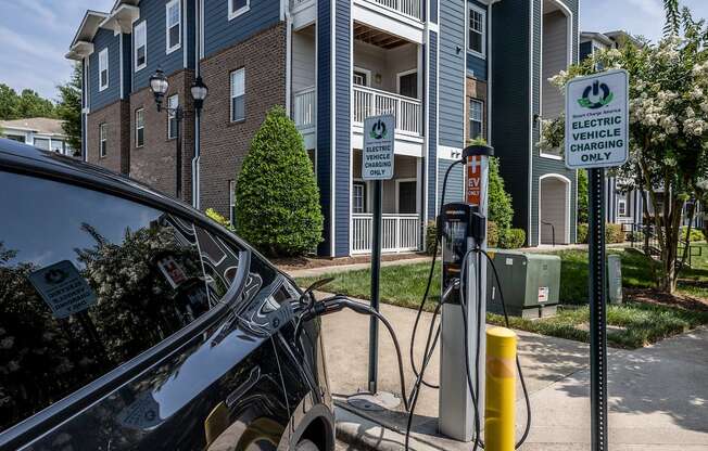 a car is plugged into a charging station in front of an apartment building