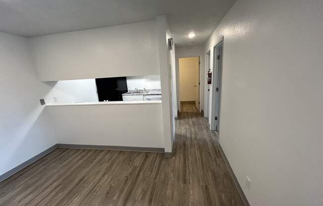 an empty living room with white walls and wood flooring at Kings Court, Alaska ? 