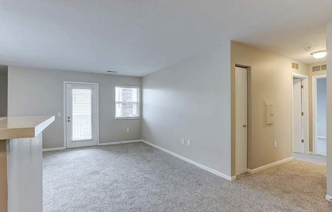 A spacious room with carpeted floor and two windows.