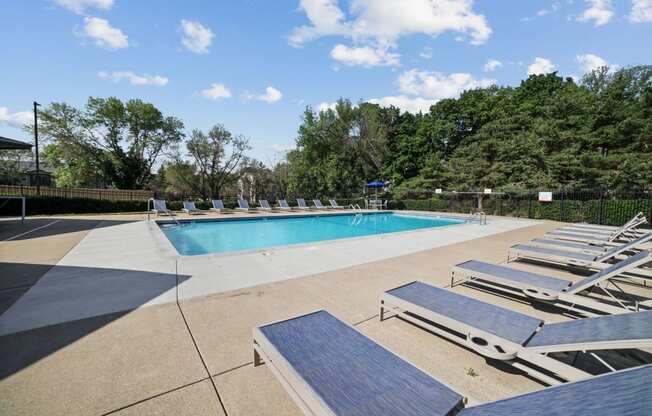 a pool with lounge chairs and trees in the background