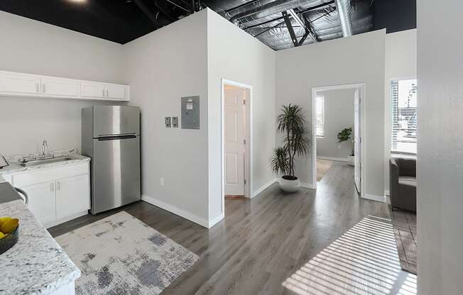 A kitchen with a refrigerator, sink, and a dining table with chairs.