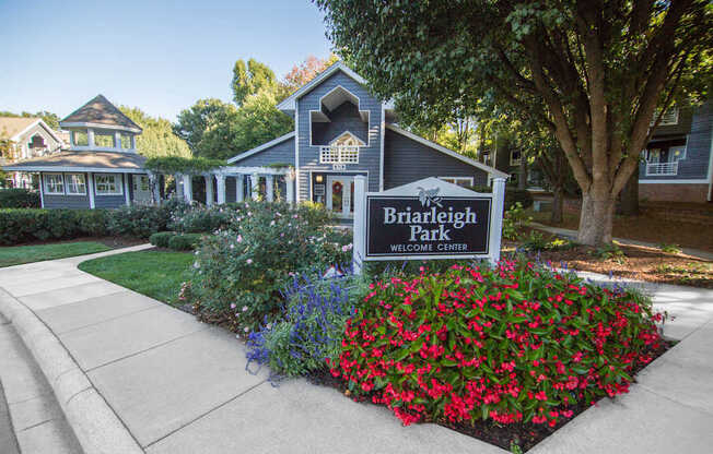 A sign that says Briarleigh Park Welcome Center in front of some houses.