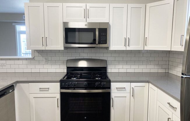 a kitchen with white cabinets and a stove and a microwave