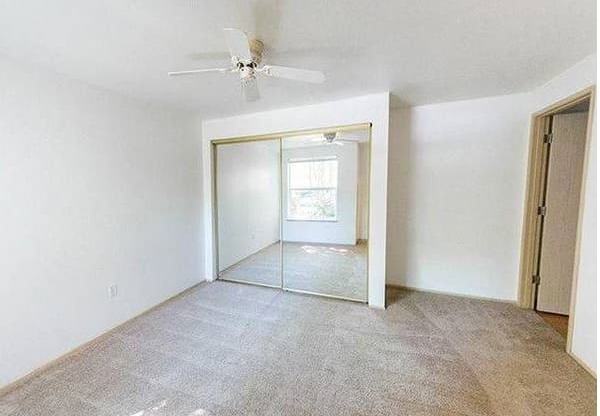 A room with a ceiling fan and a large mirror on the wall.