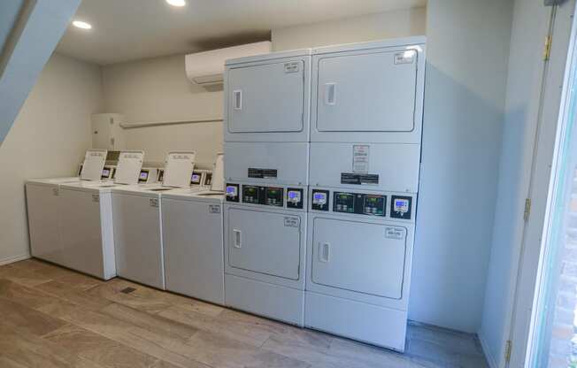 a row of white washers and dryers in a room