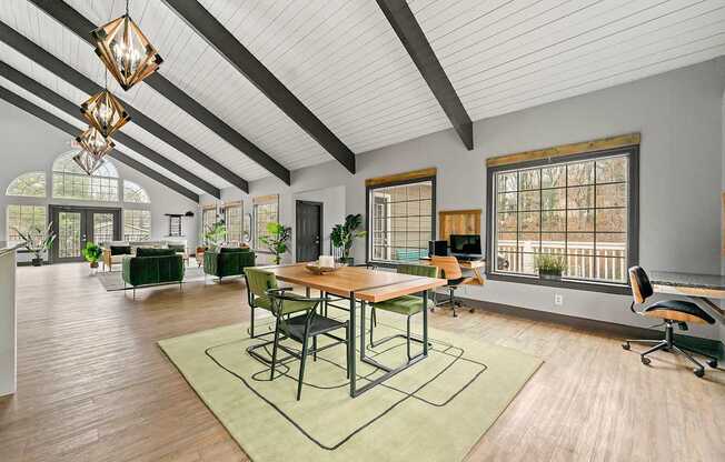 A room with a wooden table and chairs with a green rug in front of it.