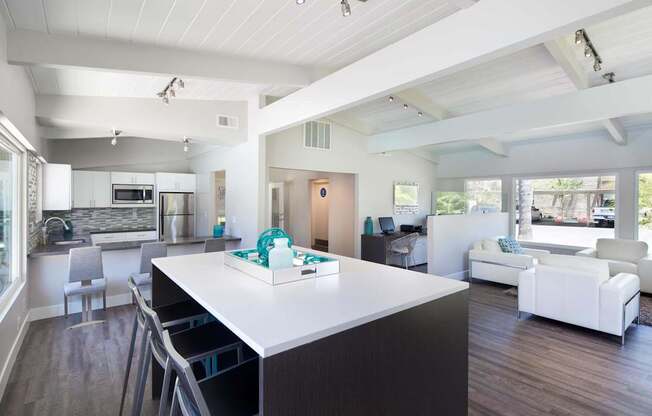 A modern kitchen with a white island and a dining table with chairs.