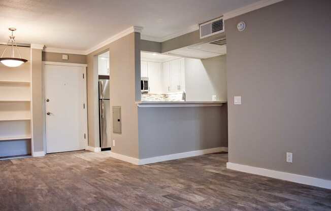 Large living room with wood-styled ceramic flooring looking into the kitchen