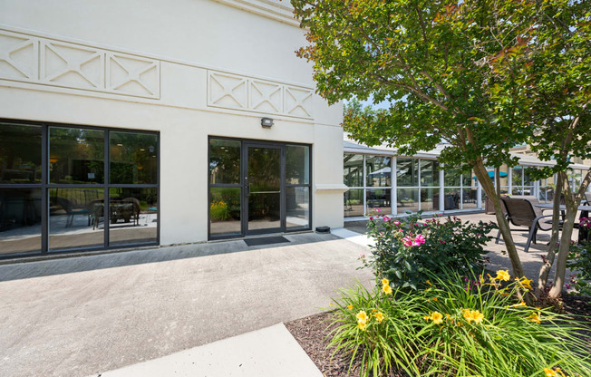 a sidewalk in front of a white building with glass doors