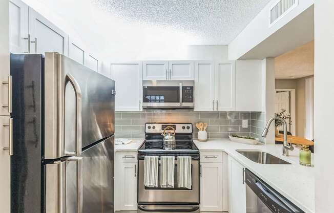 Kitchen with stainless steel appliances and white cabinets at The Atlantic Preserve, Plantation, FL 33322