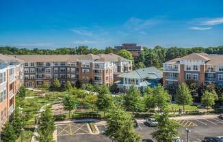 an aerial view of an apartment complex with trees and a parking lot