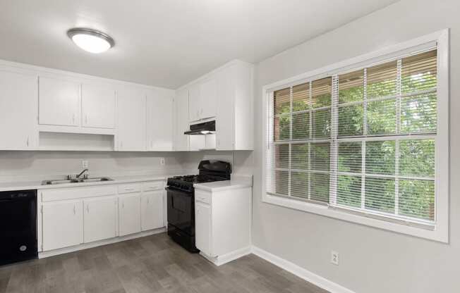 an empty kitchen with white cabinets and a large window