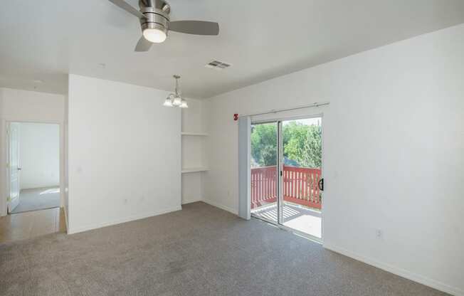 an empty living room with a sliding glass door to a balcony