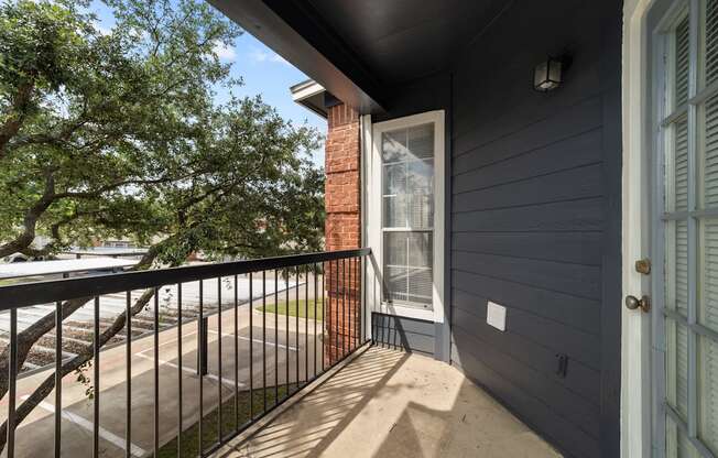 A balcony with a black railing and a brick pillar.