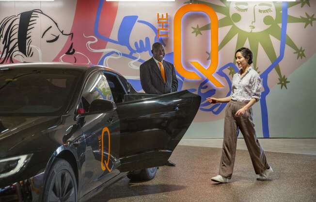 a man and a woman standing next to a black car