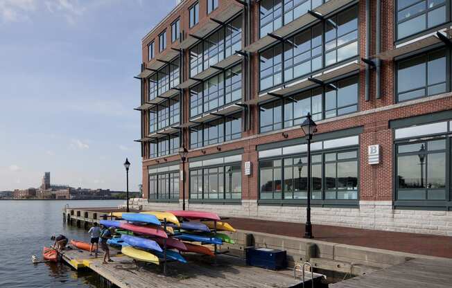 a row of colorful kayaks on a dock in front of a building
