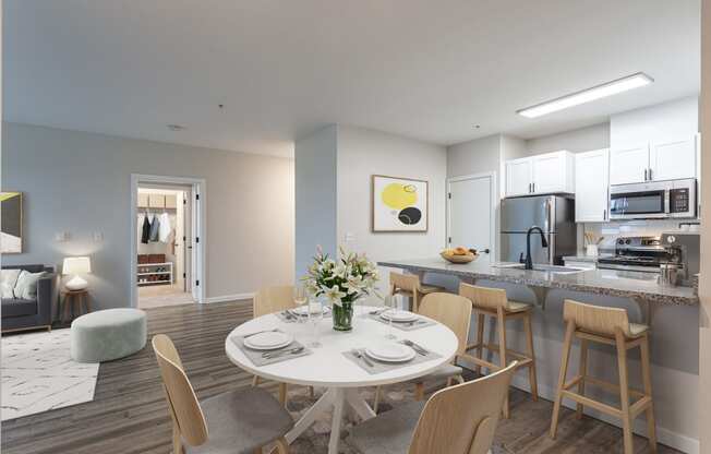 a dining area with a white table and chairs and a kitchen in the background