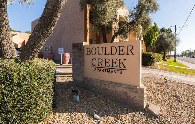 A sign for Boulder Creek Apartments is shown in front of a building.