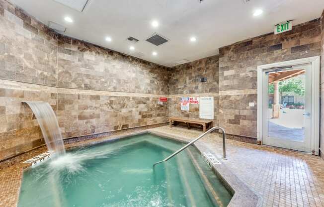 a indoor pool with a waterfall in a building with a glass door