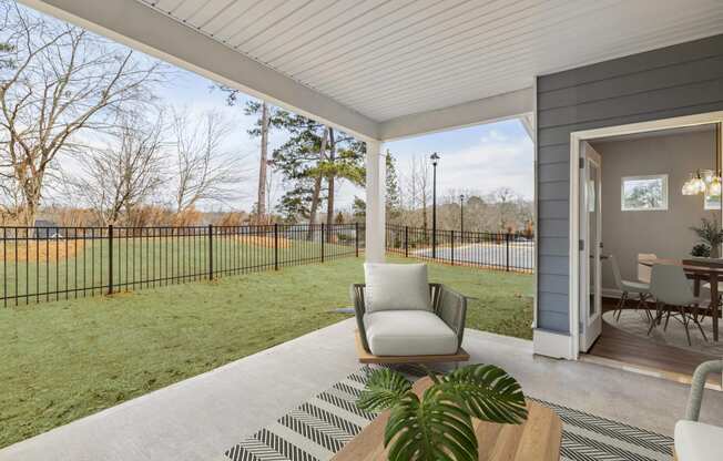 a patio with a chair and a table and a yard with a fence