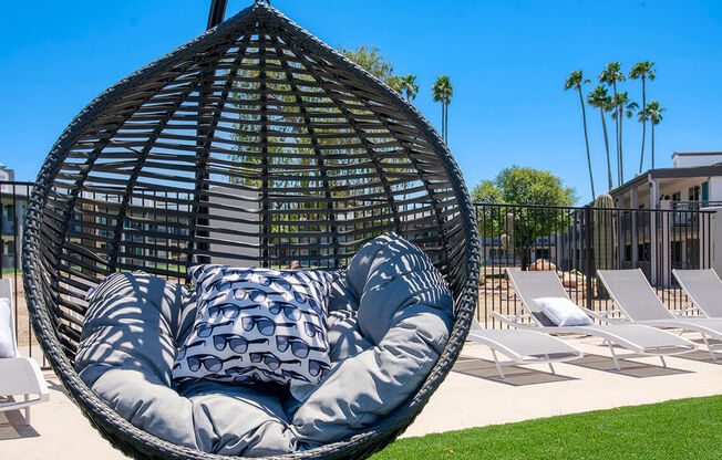 a swing chair with pillows on the grass at a pool at Presidio Palms Apartments, Tucson, Arizona