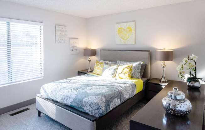 a bedroom with a bed and a night stand and a window