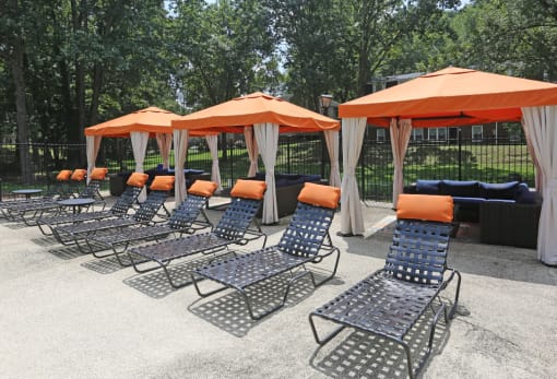 a row of chaise lounge chairs with orange umbrellas
